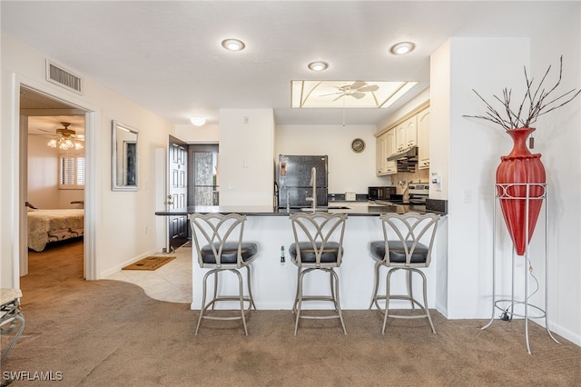 kitchen with dark countertops, ceiling fan, visible vents, and freestanding refrigerator