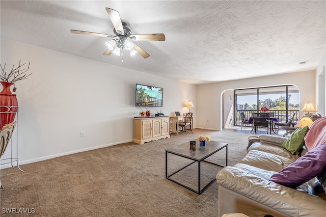 living area featuring light carpet, ceiling fan, a textured ceiling, and baseboards