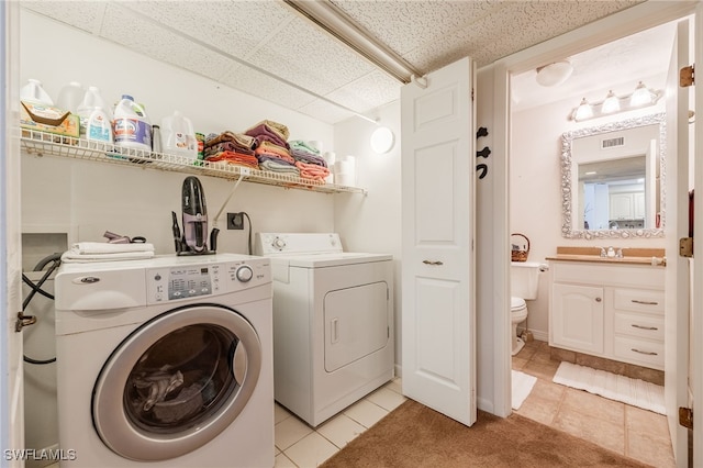 washroom featuring washer and dryer, laundry area, light tile patterned flooring, and visible vents