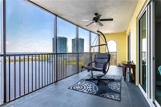 sunroom featuring ceiling fan and a water view