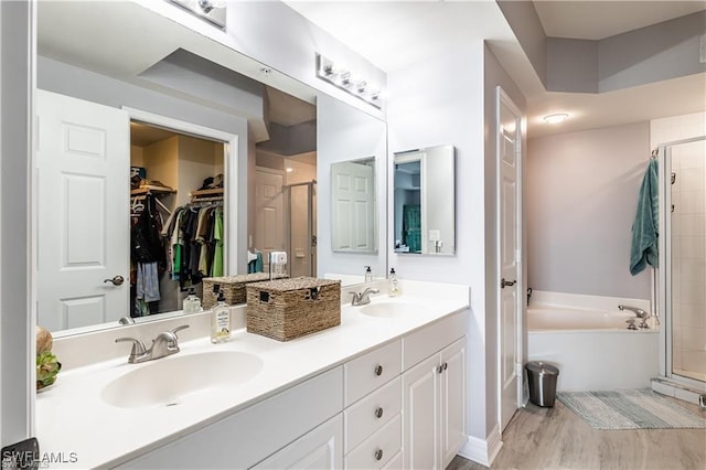 bathroom with a sink, a walk in closet, a stall shower, and a bath