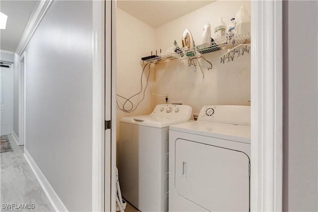 laundry area with light hardwood / wood-style floors, washer and dryer, and ornamental molding