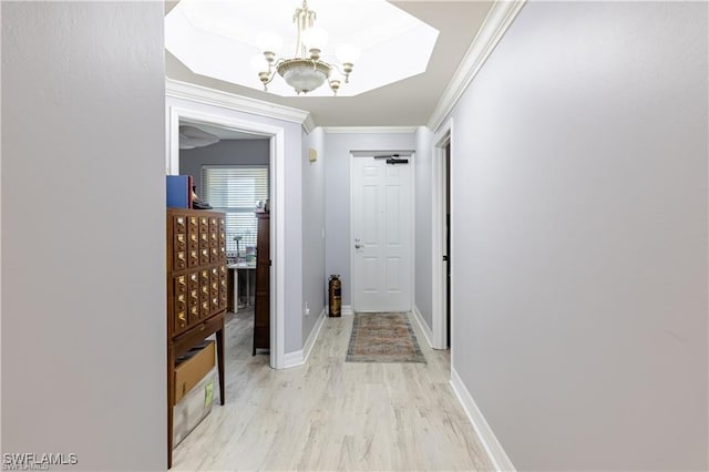 hallway featuring light hardwood / wood-style floors, ornamental molding, and an inviting chandelier