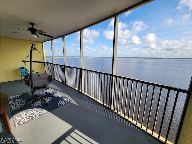 sunroom featuring ceiling fan and a water view