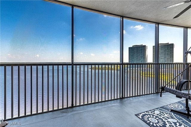 unfurnished sunroom featuring ceiling fan and a water view