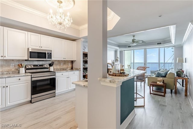 kitchen with light wood finished floors, tasteful backsplash, open floor plan, stainless steel appliances, and ornamental molding
