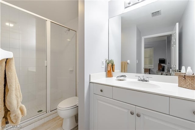 bathroom featuring hardwood / wood-style floors, vanity, toilet, and a shower with door