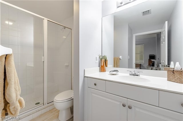 full bath featuring visible vents, toilet, wood finished floors, vanity, and a stall shower