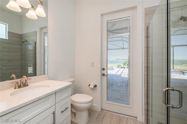 bathroom featuring a shower with door, vanity, a chandelier, and toilet