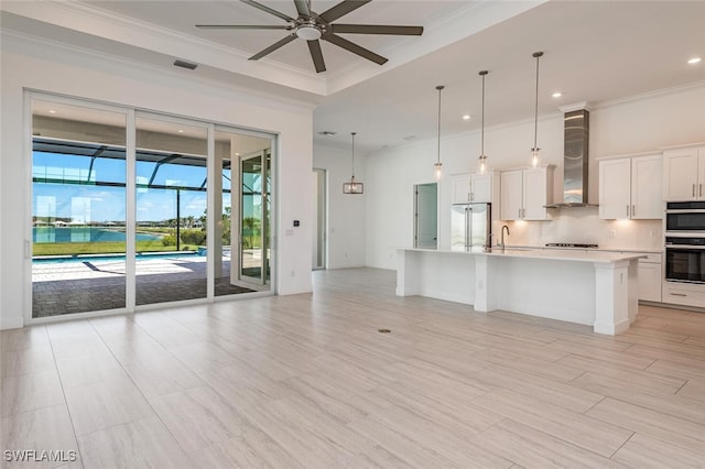 kitchen featuring white cabinetry, a large island, wall chimney range hood, pendant lighting, and black appliances