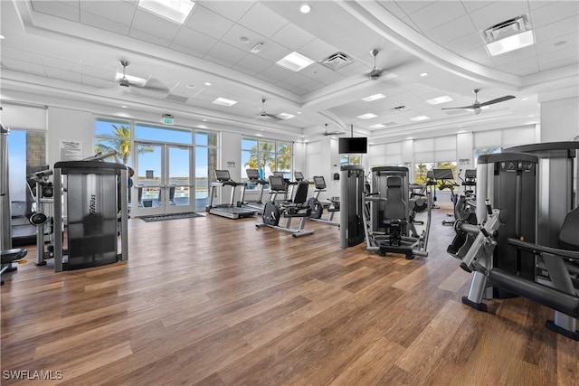 gym featuring a tray ceiling, ceiling fan, a drop ceiling, and hardwood / wood-style floors