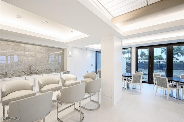 interior space with french doors, a tray ceiling, and sink