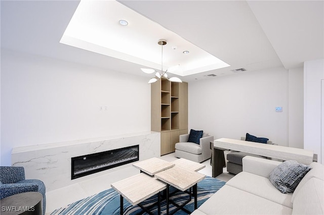 living room featuring a raised ceiling and a fireplace