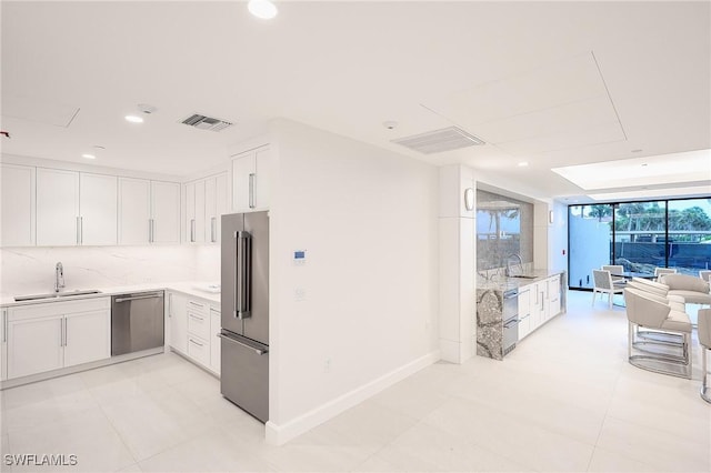 kitchen featuring appliances with stainless steel finishes, sink, white cabinets, and backsplash