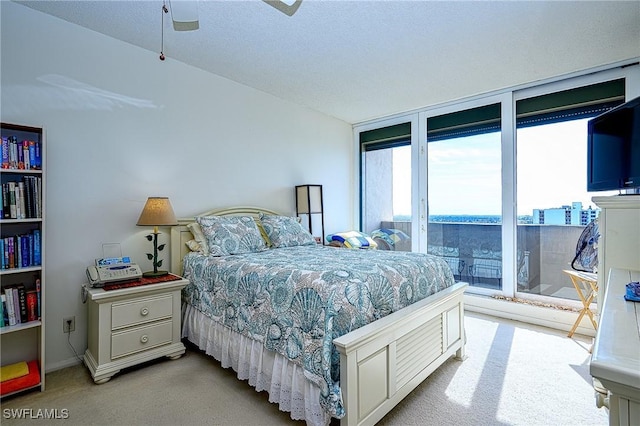 carpeted bedroom with a textured ceiling, access to outside, expansive windows, and ceiling fan