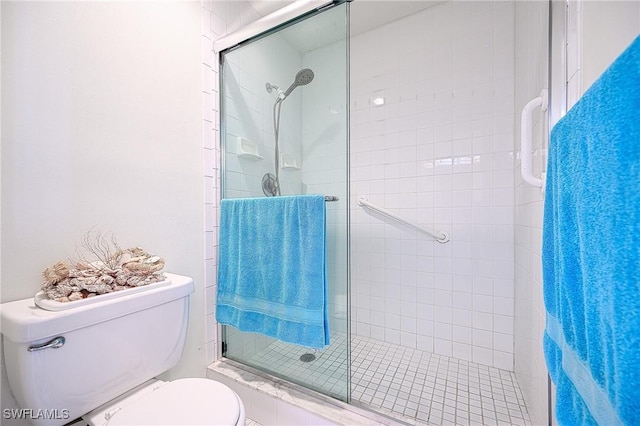 bathroom featuring a shower with door and toilet