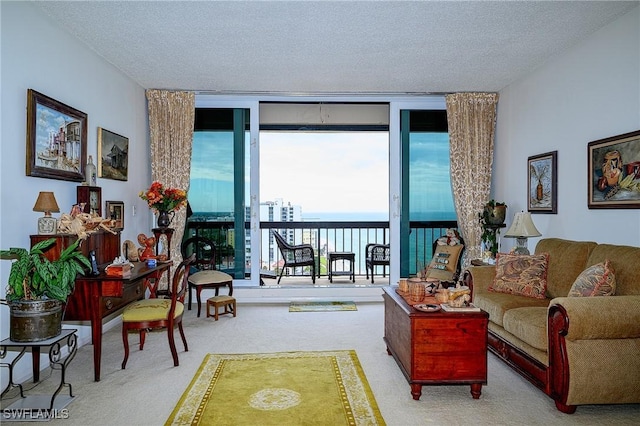 carpeted living room featuring a water view, a textured ceiling, and a wall of windows