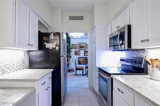 kitchen featuring white cabinetry, decorative backsplash, appliances with stainless steel finishes, and light carpet