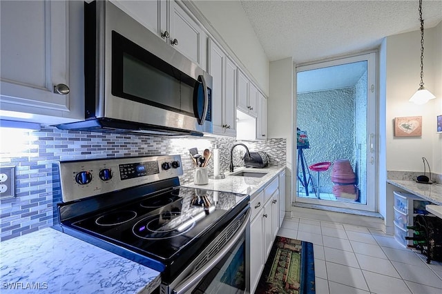 kitchen with white cabinetry, sink, backsplash, stainless steel appliances, and a textured ceiling