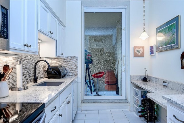 kitchen with pendant lighting, sink, light tile patterned floors, white cabinetry, and backsplash