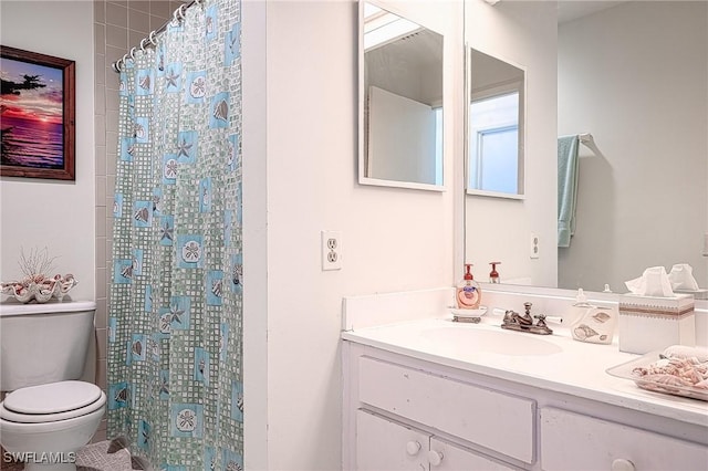 bathroom featuring vanity, walk in shower, and toilet