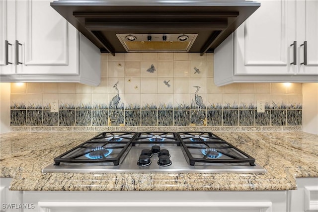 kitchen with tasteful backsplash, extractor fan, stainless steel gas cooktop, and white cabinetry