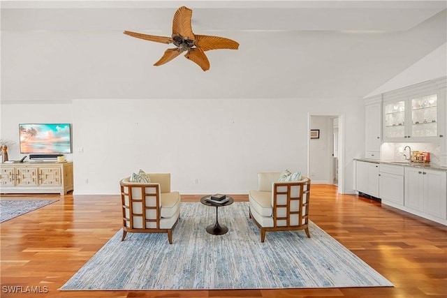 sitting room featuring ceiling fan, sink, vaulted ceiling, and light hardwood / wood-style flooring