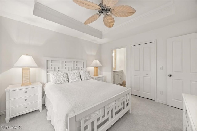 carpeted bedroom featuring ensuite bath, ornamental molding, a raised ceiling, ceiling fan, and a closet