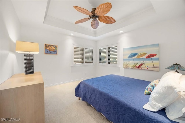 bedroom with ceiling fan, a raised ceiling, light colored carpet, and crown molding