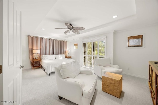 carpeted bedroom featuring a tray ceiling and ceiling fan