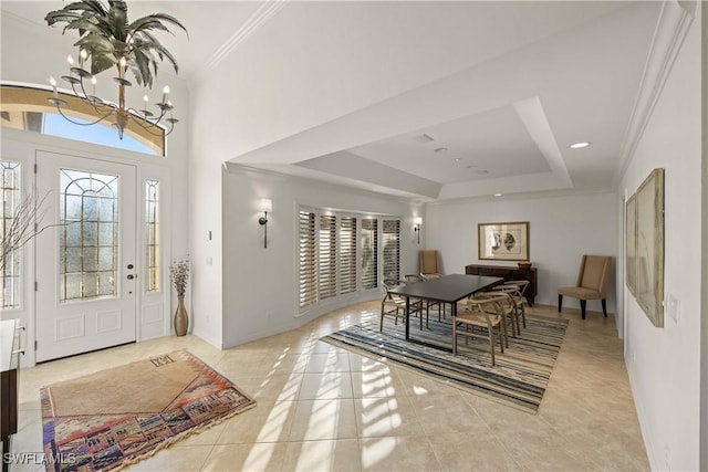 foyer entrance with a tray ceiling, crown molding, a notable chandelier, and light tile patterned flooring