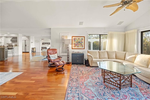 living room with lofted ceiling, light hardwood / wood-style floors, ceiling fan, and a healthy amount of sunlight