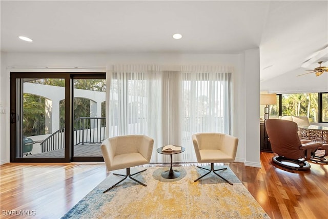 sitting room with ceiling fan, hardwood / wood-style floors, and vaulted ceiling