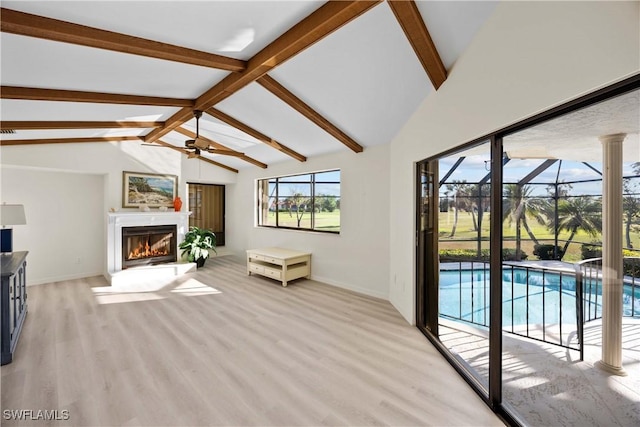 unfurnished living room featuring vaulted ceiling with beams, ceiling fan, light hardwood / wood-style floors, and a wealth of natural light