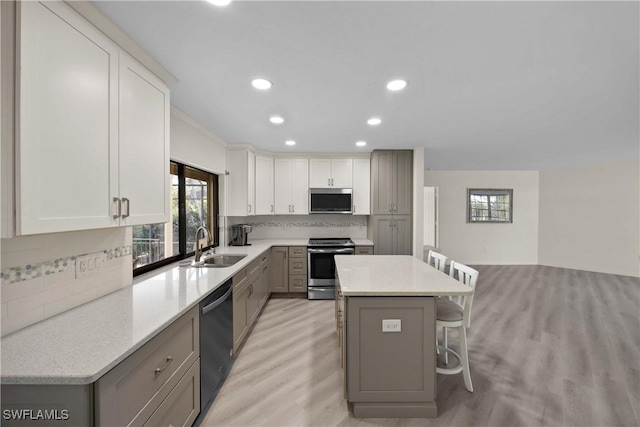 kitchen with sink, a kitchen breakfast bar, decorative backsplash, a kitchen island, and appliances with stainless steel finishes