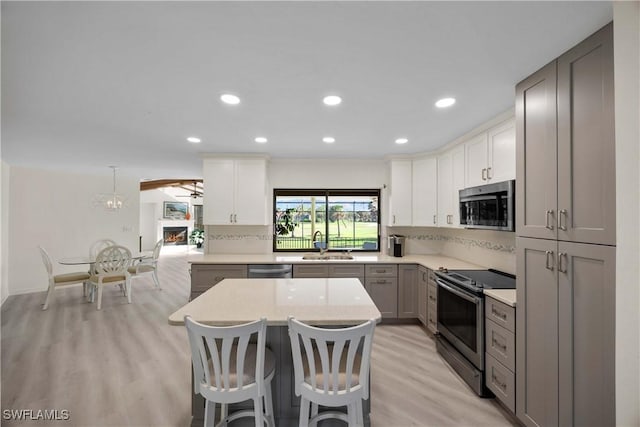 kitchen featuring decorative backsplash, appliances with stainless steel finishes, decorative light fixtures, and gray cabinetry