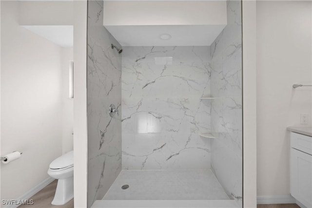 bathroom featuring hardwood / wood-style floors, vanity, toilet, and a tile shower