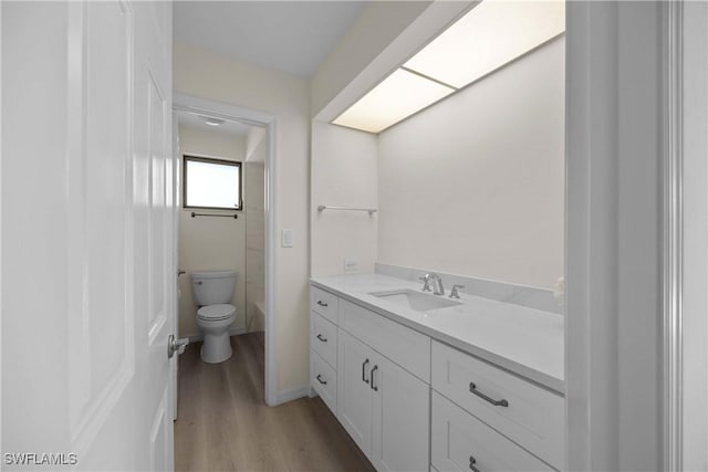 bathroom with hardwood / wood-style flooring, vanity, and toilet