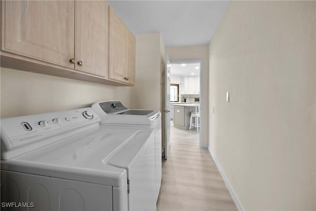 washroom with cabinets, washer and dryer, and light wood-type flooring