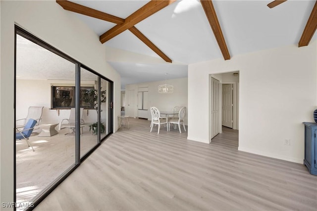 interior space featuring ceiling fan with notable chandelier, vaulted ceiling with beams, and light hardwood / wood-style floors