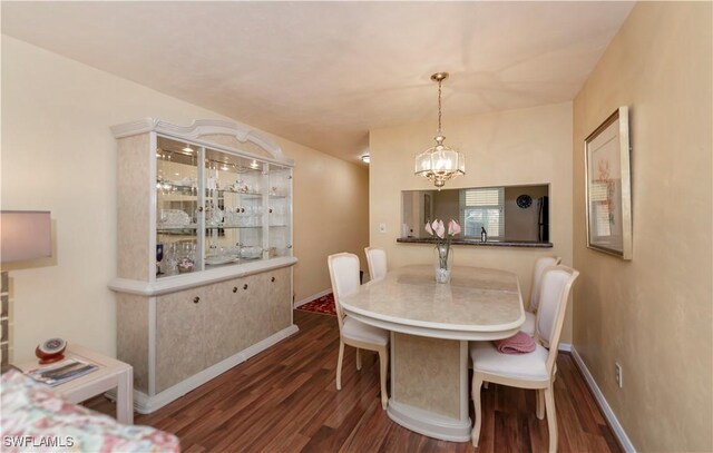 dining room with dark wood-type flooring and a chandelier