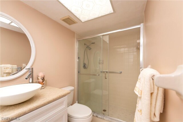 bathroom featuring vanity, toilet, and a shower with door