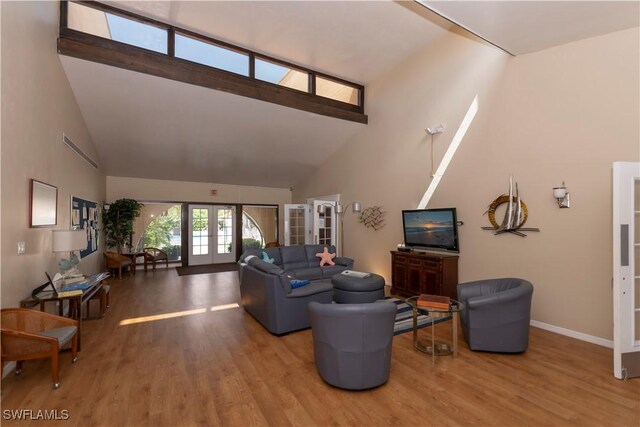 living room with french doors, high vaulted ceiling, and wood-type flooring