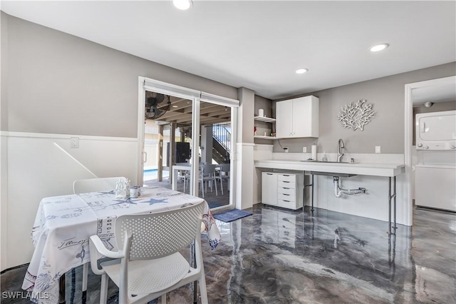 kitchen with sink, white cabinetry, and stacked washer / dryer