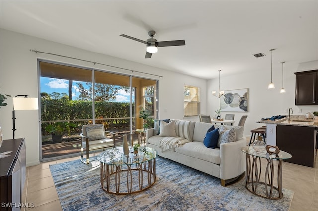 living room with light tile patterned floors, ceiling fan with notable chandelier, and sink