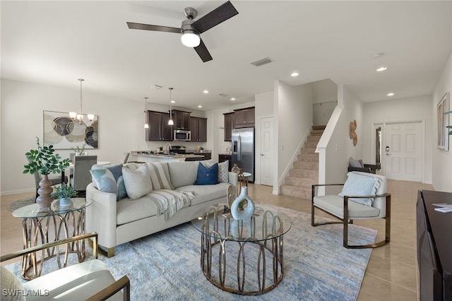 tiled living room featuring ceiling fan with notable chandelier