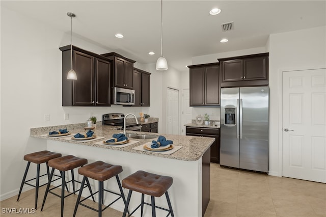 kitchen featuring a kitchen bar, decorative light fixtures, dark brown cabinets, kitchen peninsula, and stainless steel appliances