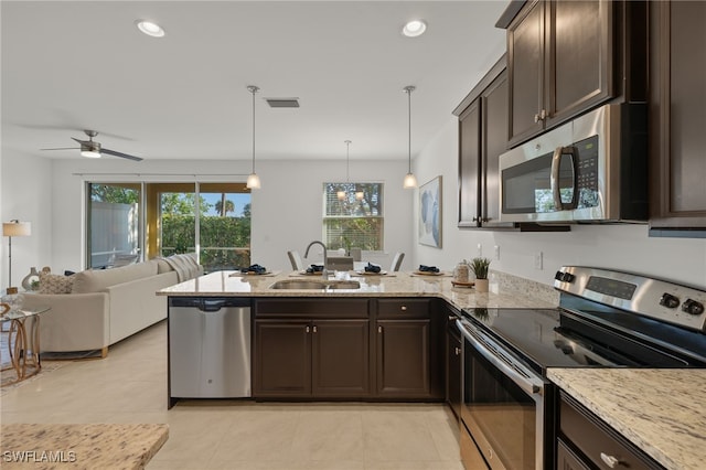 kitchen with dark brown cabinetry, stainless steel appliances, sink, and hanging light fixtures