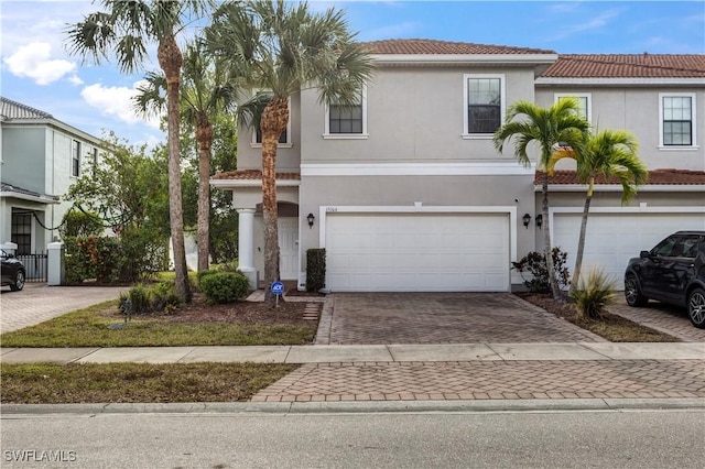 view of front of home with a tiled roof, decorative driveway, and stucco siding