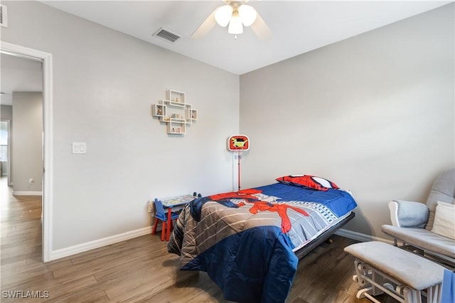 bedroom with a ceiling fan, wood finished floors, visible vents, and baseboards